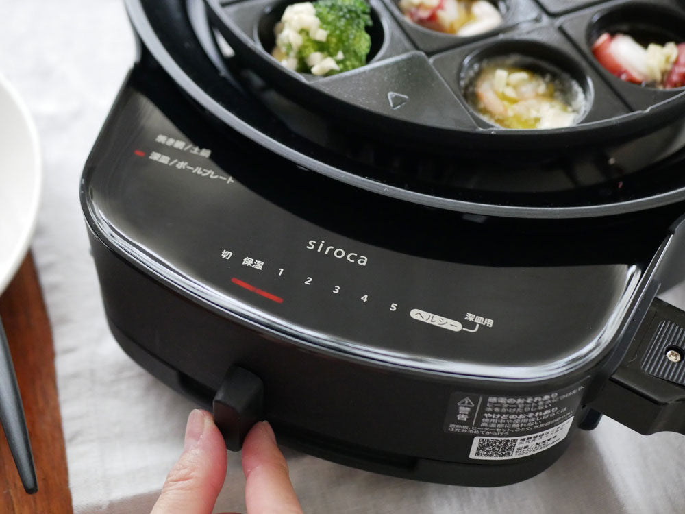 シロカのおうちいろりと多彩なプレートを使用してキッチンで料理をしている様子