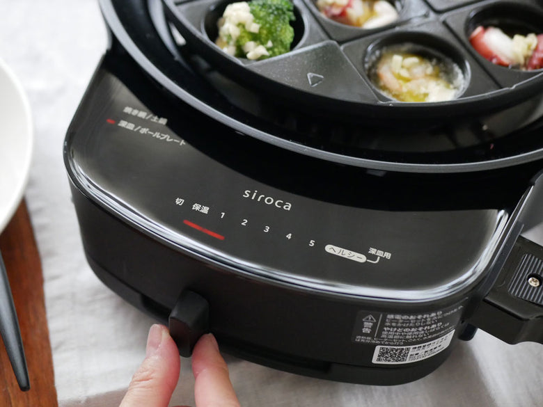 シロカのおうちいろりと多彩なプレートを使用してキッチンで料理をしている様子