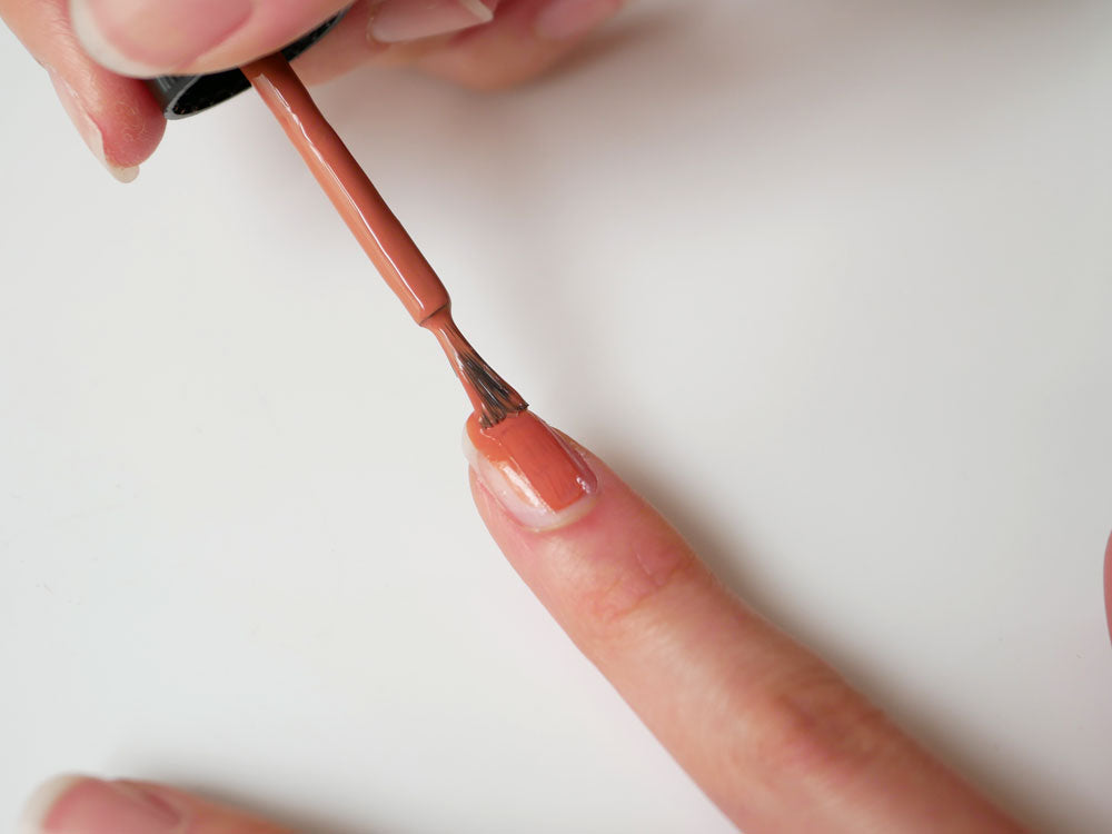 ピンク色のネイルポリッシュが塗られた女性の手のアップ