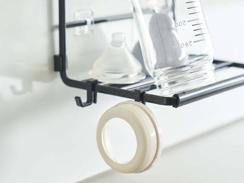 【tower/タワー】フィルムフックワイドジャグボトルホルダー Sがキッチンの棚に設置され、調理器具やパイプと共にディスプレイされている様子