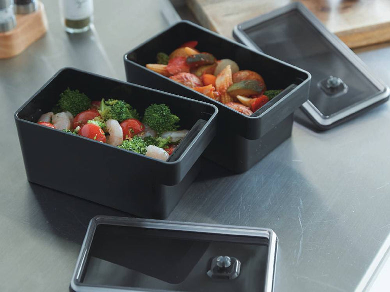 ハンドル付き密閉フードコンテナに野菜が入っており、蓋を開けた状態でトレーの上に置かれている様子
