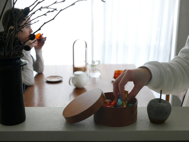 チェリー材製のアクシス シェーカーラウンドボックスと食器、フルーツ、花鉢がテーブル上に配置された様子