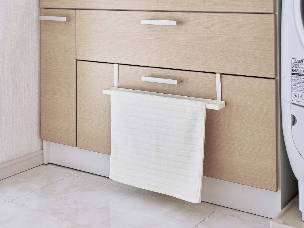 木製キャビネットの洗面下に取り付けられたスチール製のバスマットとタオルハンガー