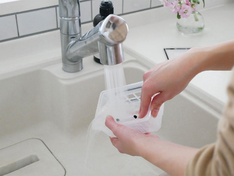 キッチンシンク上に設置された黒色のAiMY自動充電式ロボットクリーナーとプラスチック製の蛇口