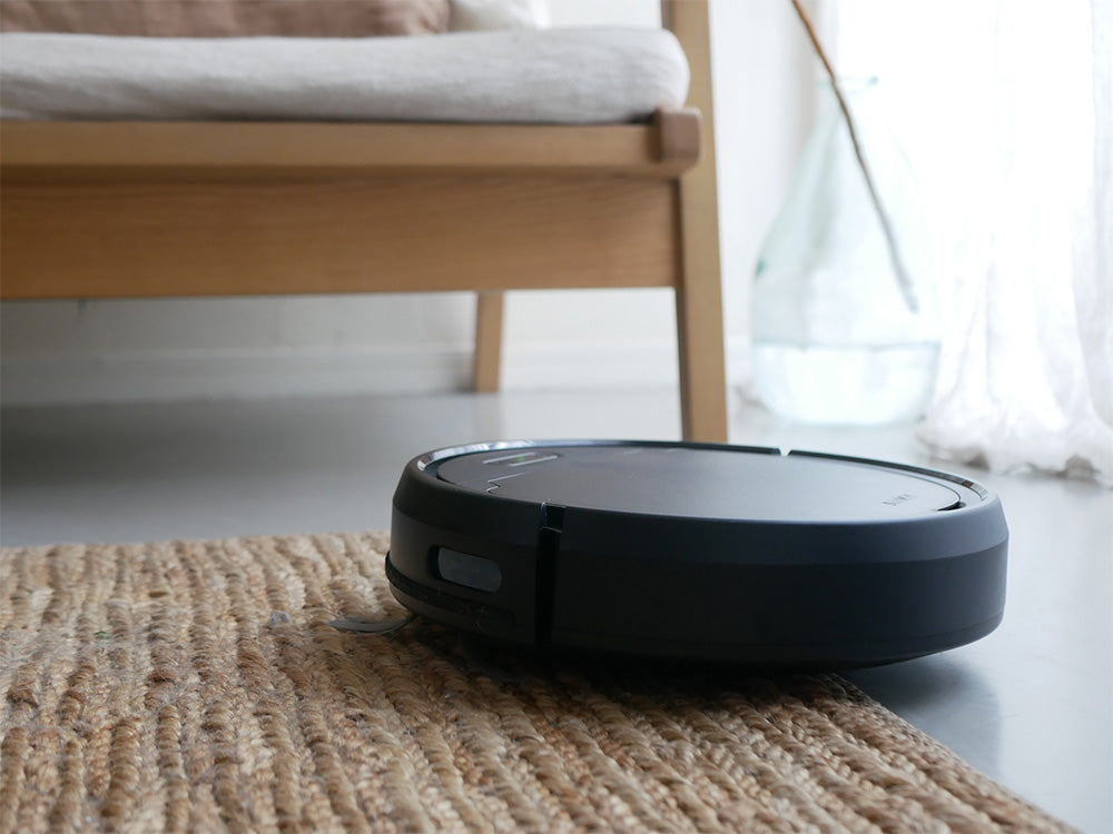 黒色のエイミー自動充電式ロボットクリーナーが木製フローリング上で清掃中