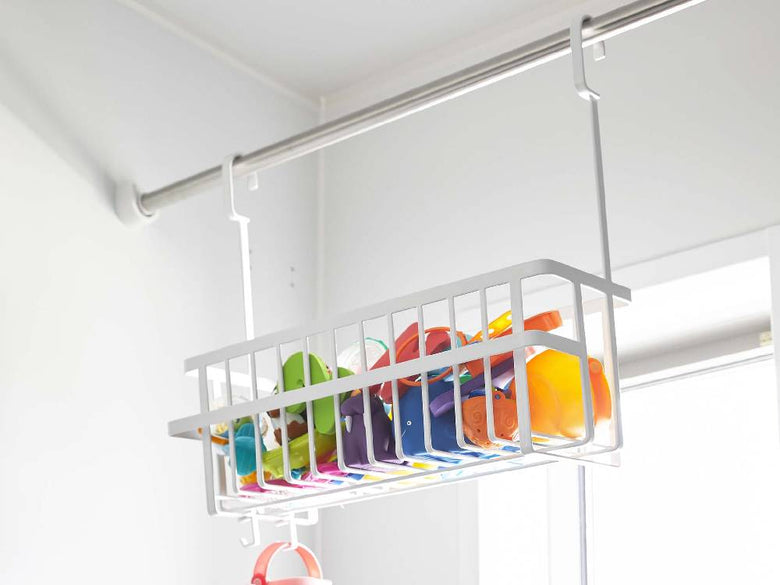 キッチン棚に掛けられたスチール製の幅広引っ掛けバスルームバスケットと、ディッシュラックや衣類ハンガーなどの家庭用品が整然と配置されている様子