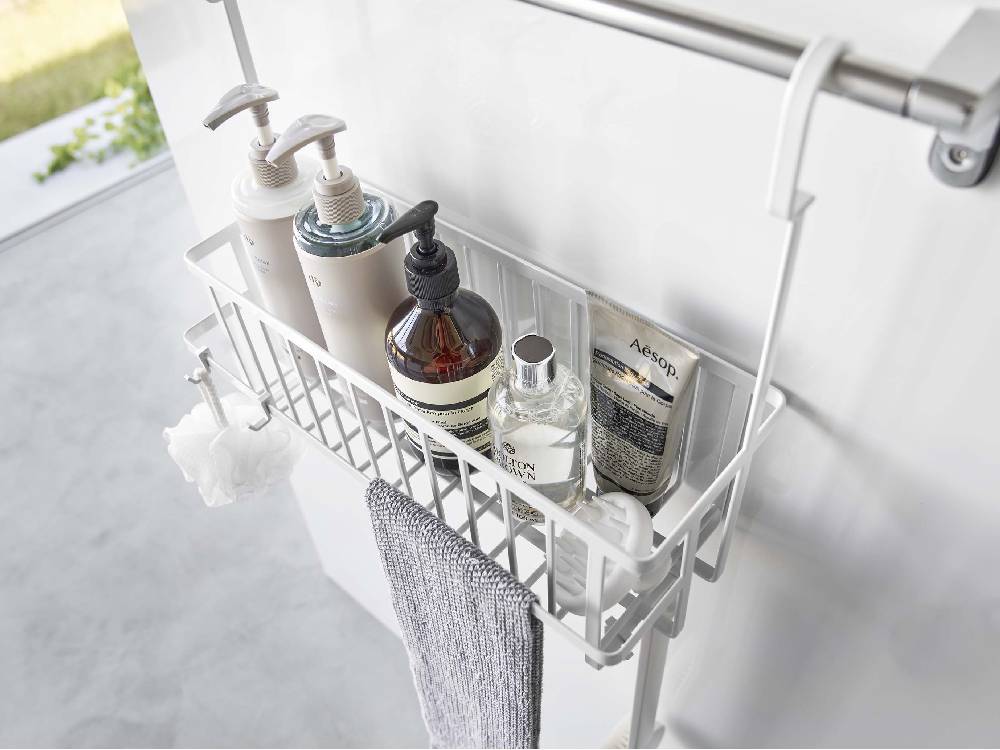 スチール製タワー型引っ掛けバスルームバスケットがシンク近くの棚に掛けられている様子
