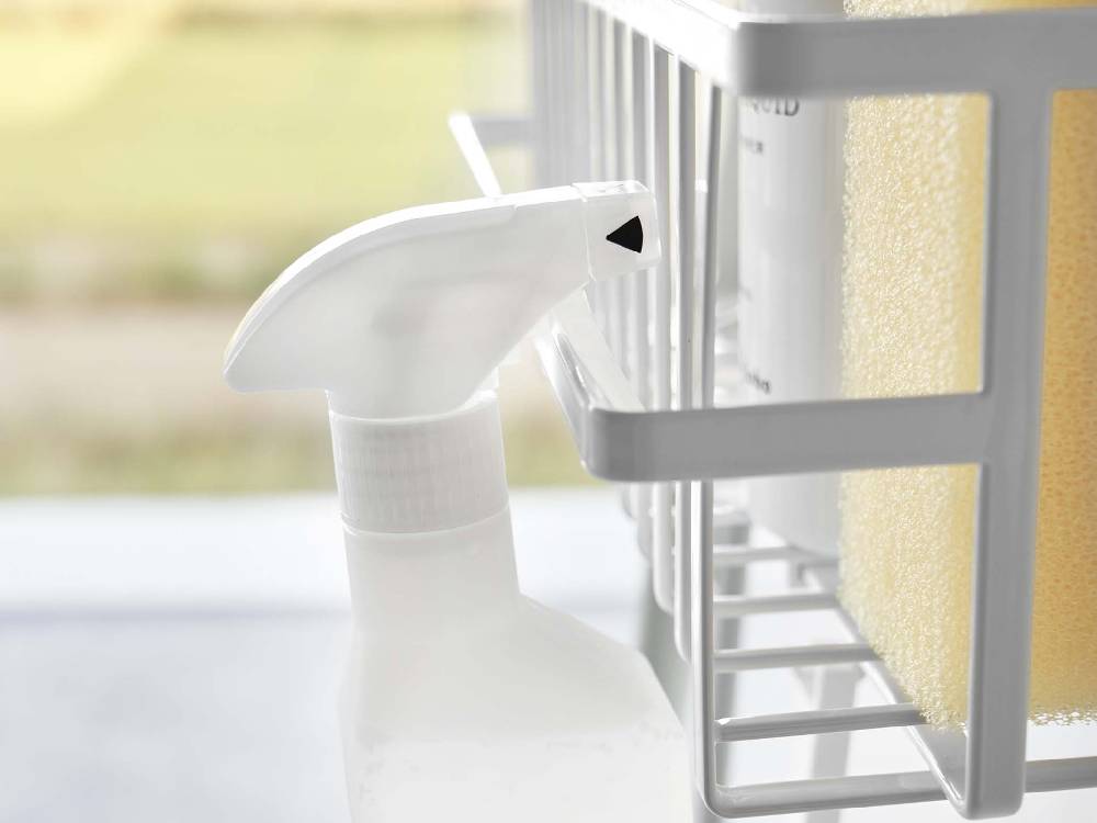 バスルームのタオルバーにプラスチック製の引っ掛けバスケットとソープディスペンサーが取り付けられている様子