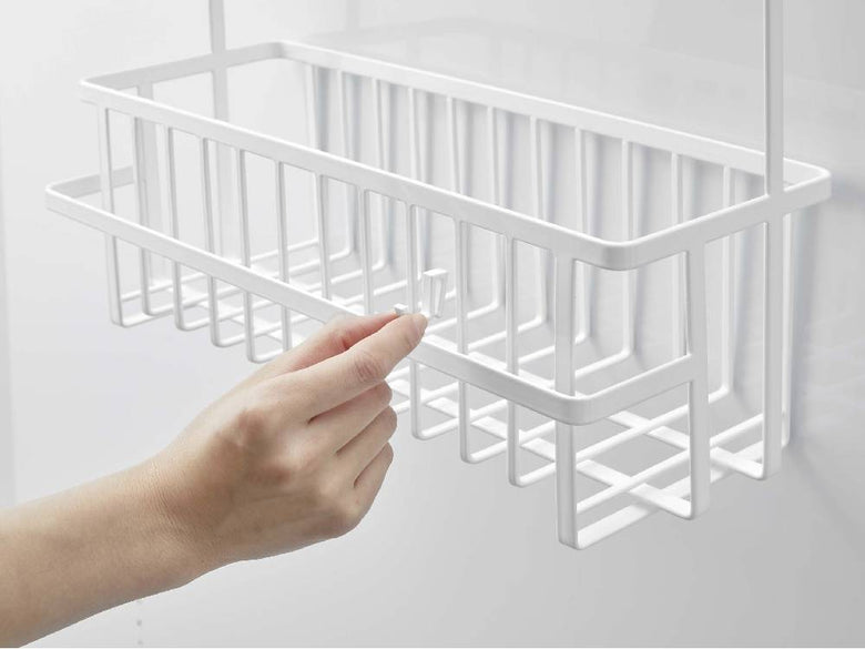 スチール製タワー引っ掛けバスルームバスケット ワイドが棚に掛かり、プラスチック製の食器ラックや家庭用品と共に整理されている様子