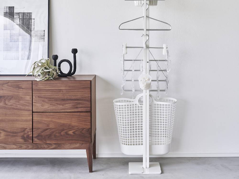 スチール製のタワー型折り畳み室内物干しが設置された室内の様子。複数のハンガーパイプと収納スペースが見えるデザイン。