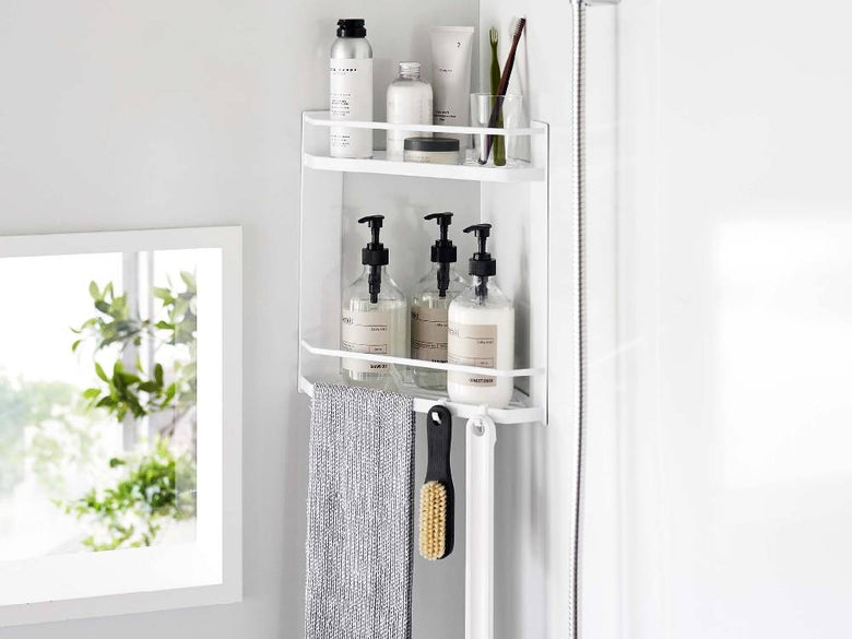 スチール製の2段マグネットバスルームコーナーラックに歯ブラシホルダーやタオル、ボトルが整然と配置された浴室の一角