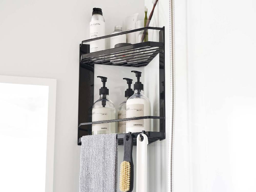 バスルームのコーナーに設置された2段式タワー型マグネットラック。下段にはボトルや洗面用品、上段にはタオルが整然と収納されている様子。