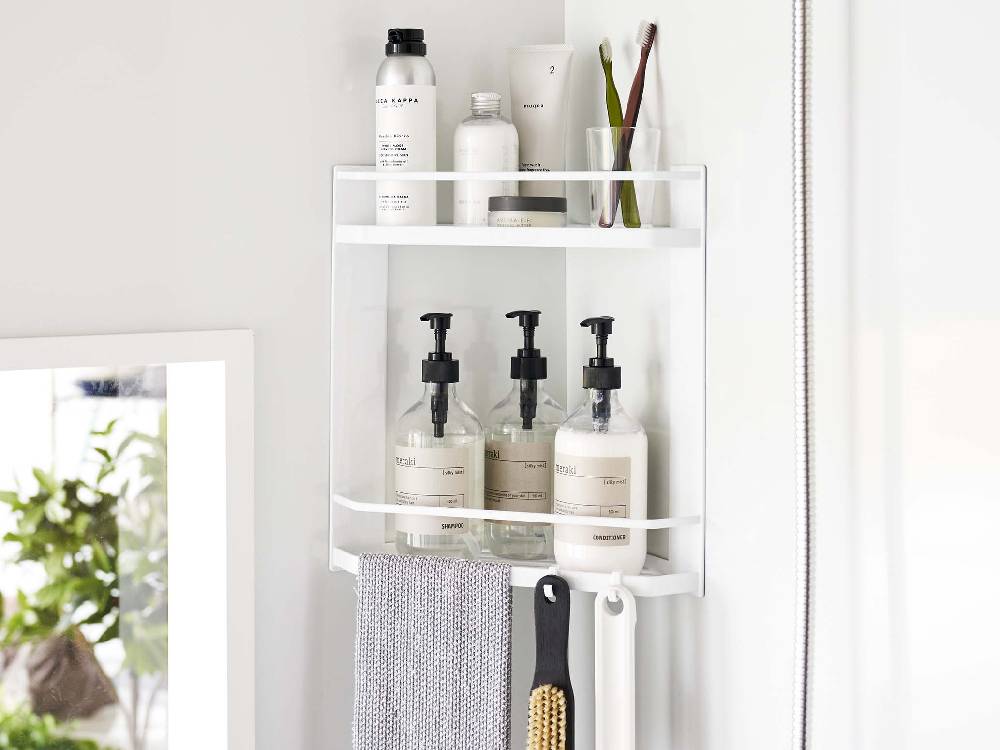 バスルームのコーナーに設置された2段マグネットラックに、シャンプーボトルや歯ブラシホルダーが置かれている
