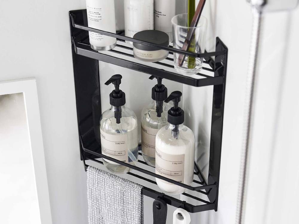 マグネット式2段バスルームコーナーラックがスチール製の壁面に設置され、棚とフックに洗面用具やボトルが整然と配置されている様子