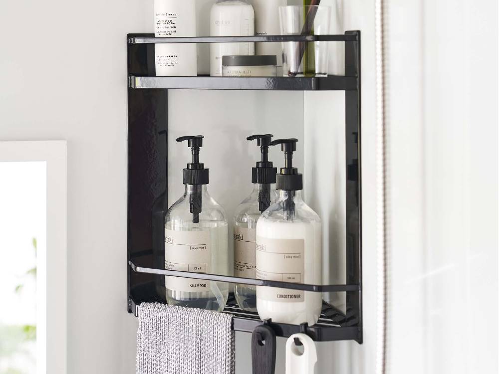 浴室のコーナーに設置された2段のマグネット式スチールバスルームラックに、ボトルや小物が整理されています。