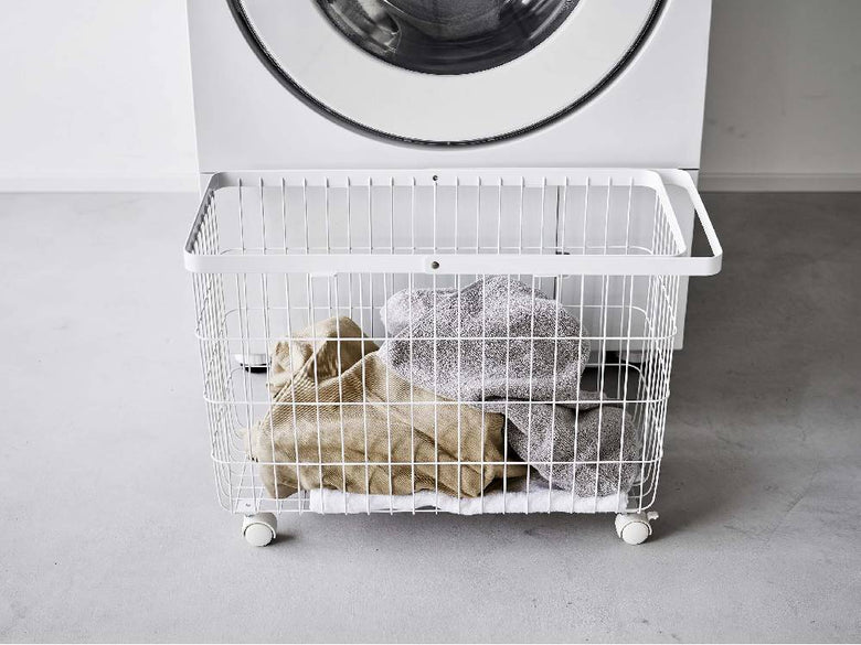 ランドリールームに置かれた洗濯機と乾燥機の横にキャスター付きワイド&ローランドリーバスケット