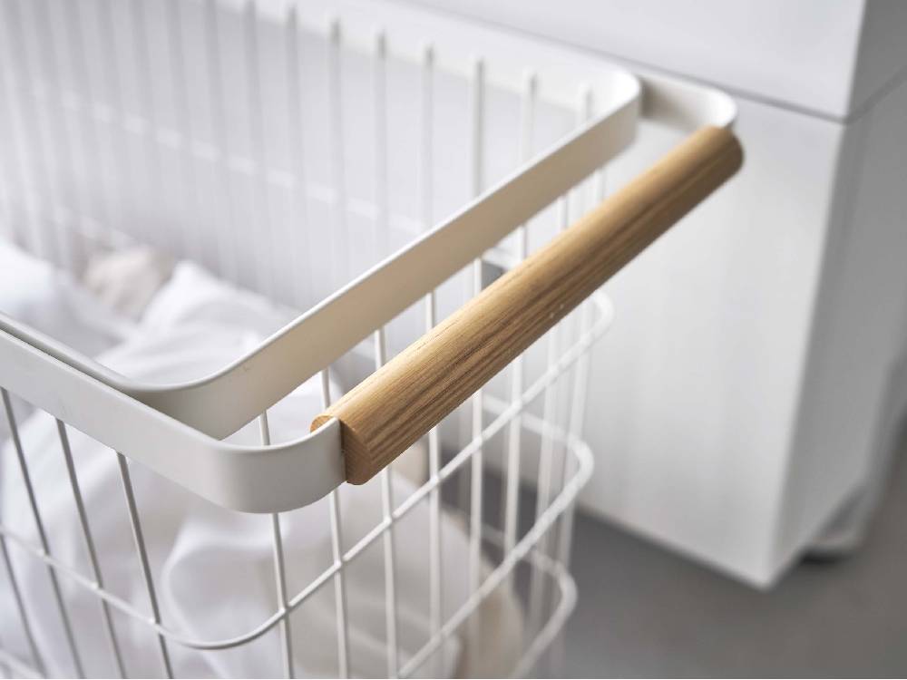 tosca（トスカ）のキャスター付きワイド&ローランドリーバスケット。プラスチック製ハンドルとスチールフレームを備え、収納棚に整然と配置された35リットル容量の清潔感あるバスケット。