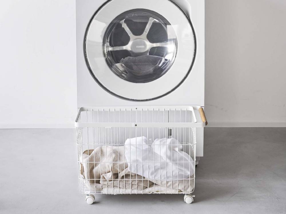 toscaトスカのキャスター付きランドリーバスケットが洗濯機と乾燥機のある洗濯室に配置されている様子