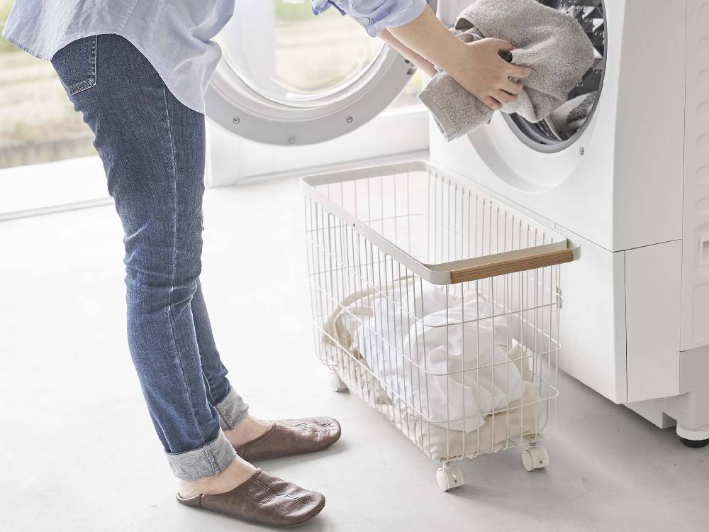 キャスター付きトスカランドリーバスケットが洗濯機と乾燥機の隣に置かれた洗濯室