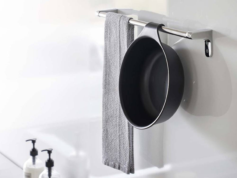 シルバーとアルミ製の浴室用ハードウェアが整然と配置されたバスルーム。マグネット付き引っ掛け湯おけ、トイレットロールホルダー、蛇口、ローブフックなどが設置されている様子。