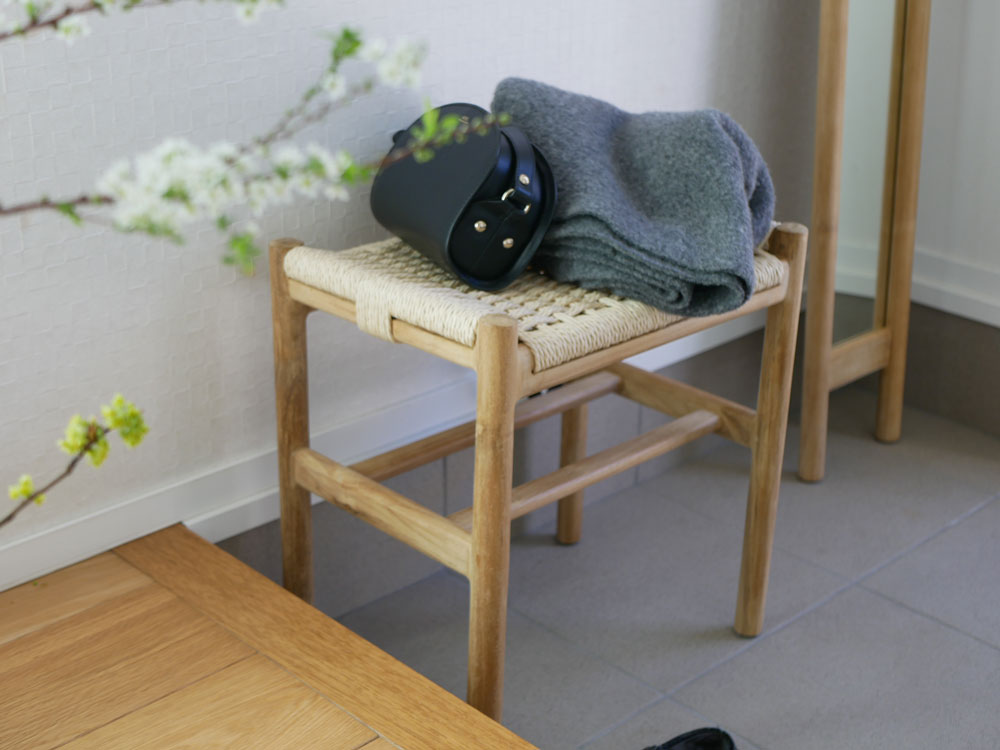 チーク無垢材とサンフラワーラタンを使用したHOKOSペーパーコードスツールが木製の床の上に置かれている