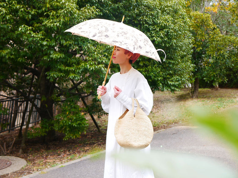 自然の中でビコーズのプレーンカラー傘を持ち、サンハットをかぶった人々がリラックスしている様子