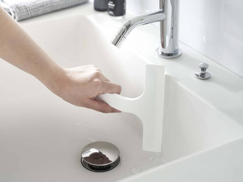 タワーのマグネット水切りワイパー Sが白い浴室のシンクと蛇口に取り付けられている様子