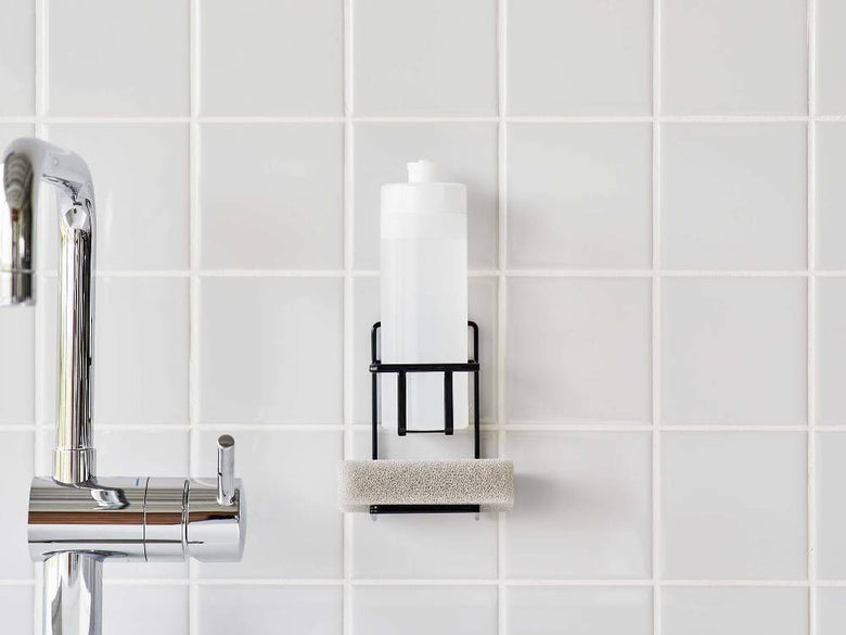 スチール製タワー フィルムフックスポンジ＆ボトルホルダーがタイル張りのバスルームの壁に取り付けられており、ボトルとスポンジが整理されている様子