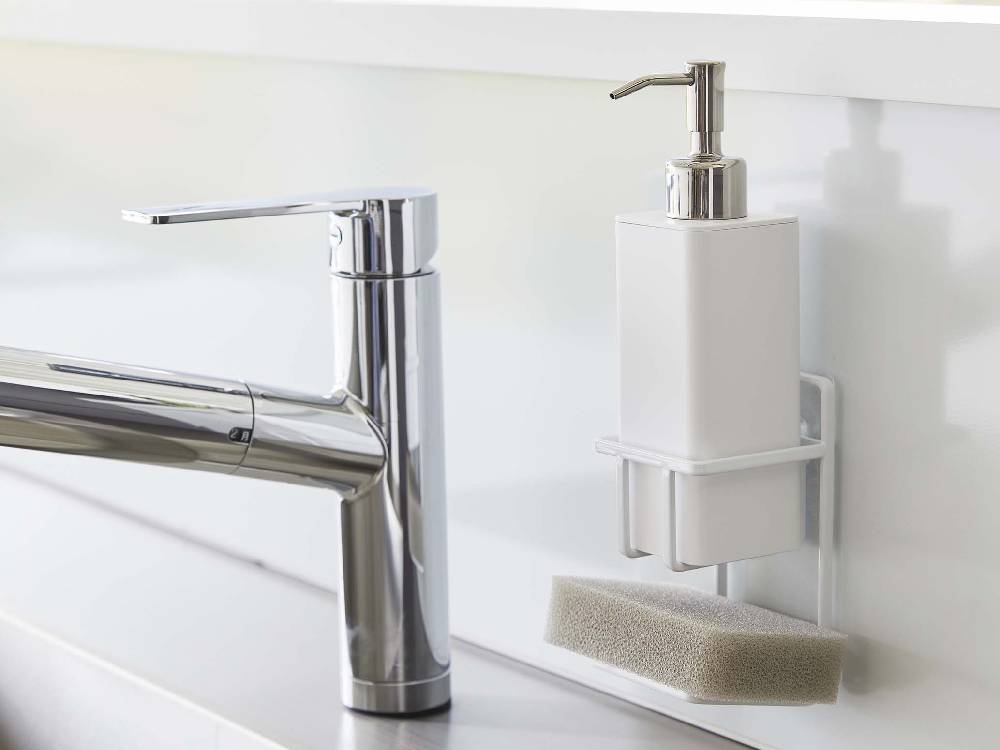 浴室のシンク横に設置されたタワー型フィルムフックスポンジ＆ボトルホルダー。スチール製でボトルとスポンジを収納し、近くに鉢植えが置かれている