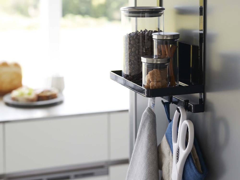 スチール壁に取り付けられた【tower/タワー】ウォーターサーバー横マグネットラック2段が調理器具や食品容器を整然と収納しているキッチンの様子