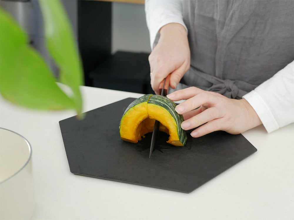 スーパーストーンバリア包丁と専用シャープナーが野菜や果物と共にカッティングボード上に配置されている様子