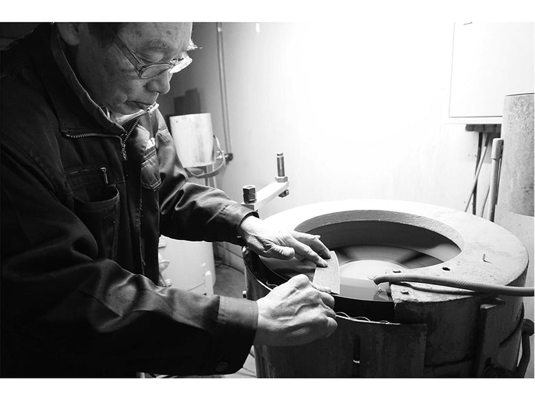 協和工業のスーパーストーンバリア包丁と専用シャープナーが職人の手と機械とともに展示されている画像