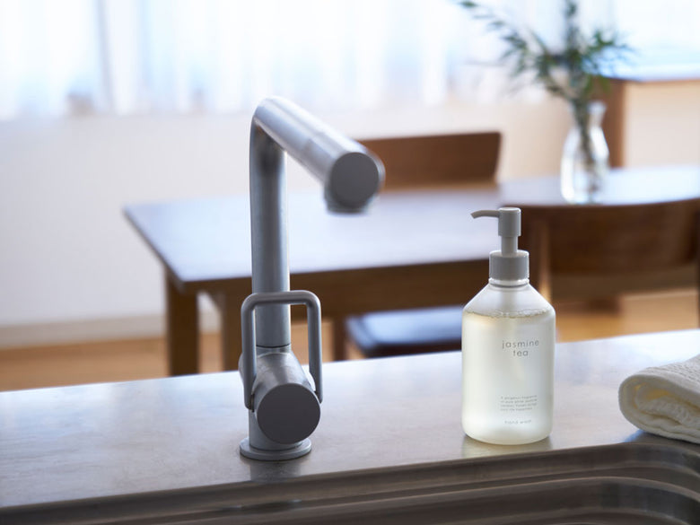 生活の木ジャスミンティー香りシリーズのリードディフューザーやハンドクリームが入ったガラスとプラスチック製のボトルが、ソープディスペンサーや蛇口とともに並んでいる様子