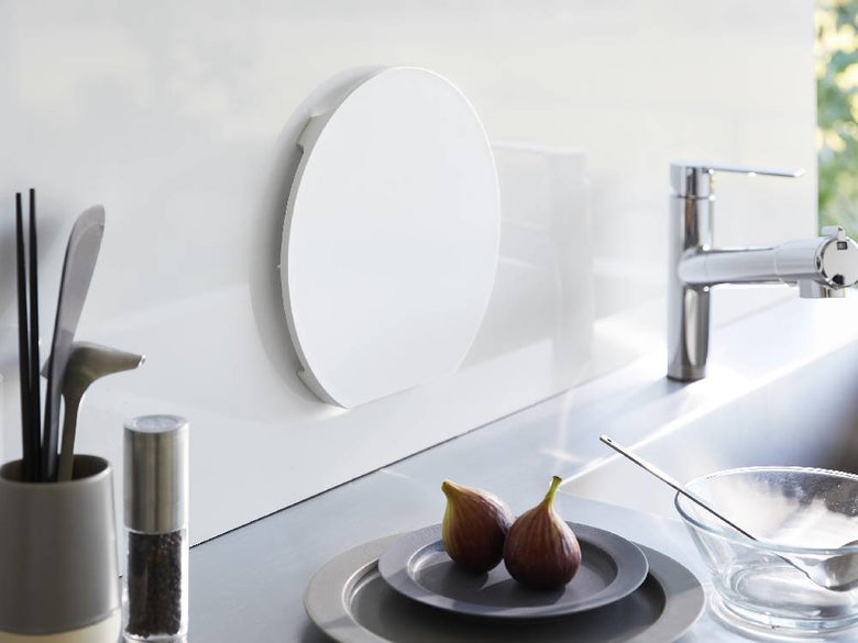 ポリプロピレン製の丸型マグネット抗菌まな板がスチールの平らな壁面に取り付けられている様子。食洗機対応。