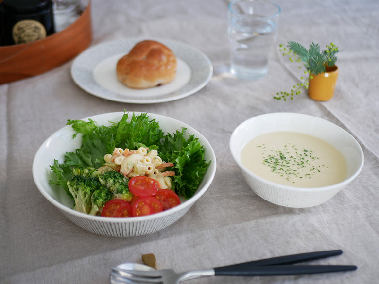 ルーマニア製アラビアのマイニオボウルに新鮮な葉物野菜が美しく盛り付けられ、食卓に並べられている様子。
