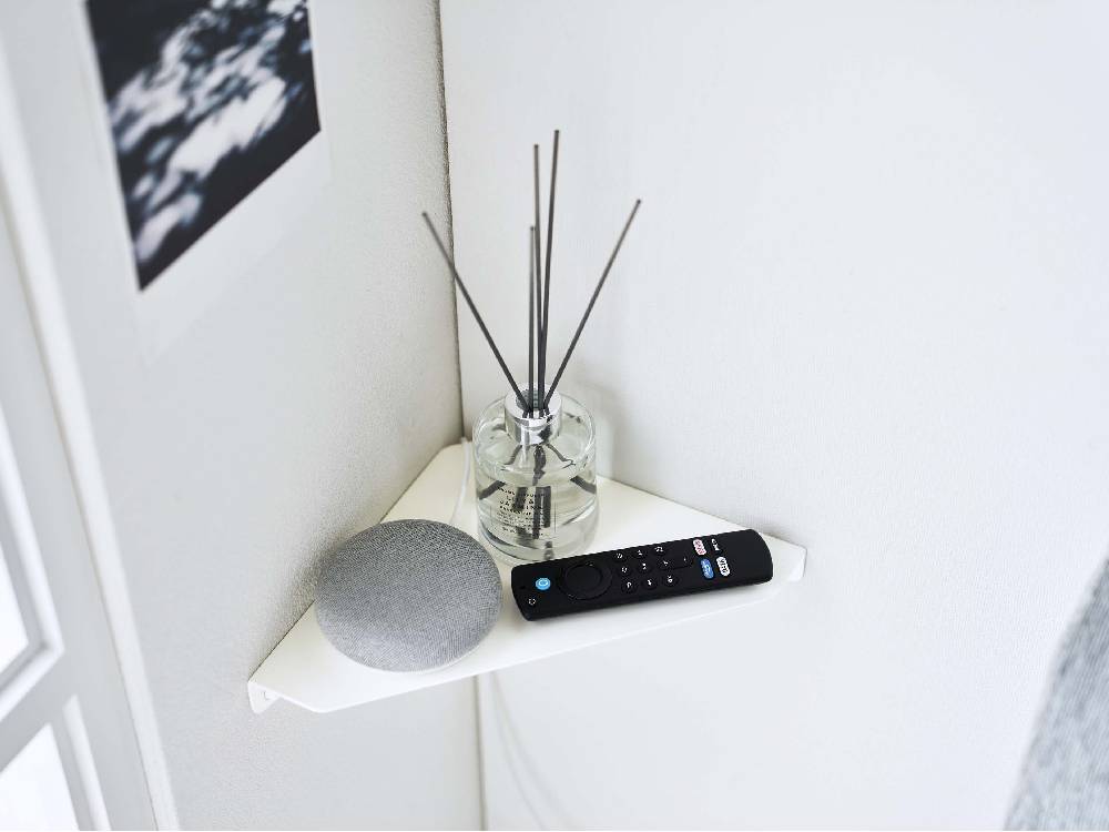 リビングルームの石こうボード壁に取り付けられたタワー型コーナーシェルフにスピーカーなどの電子機器が配置されている様子