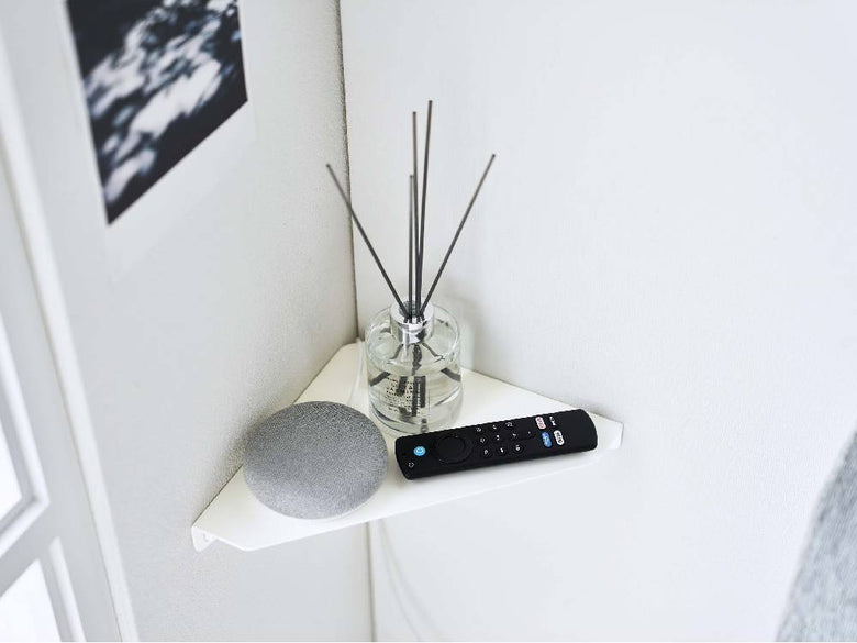 リビングルームの石こうボード壁に取り付けられたタワー型コーナーシェルフにスピーカーなどの電子機器が配置されている様子