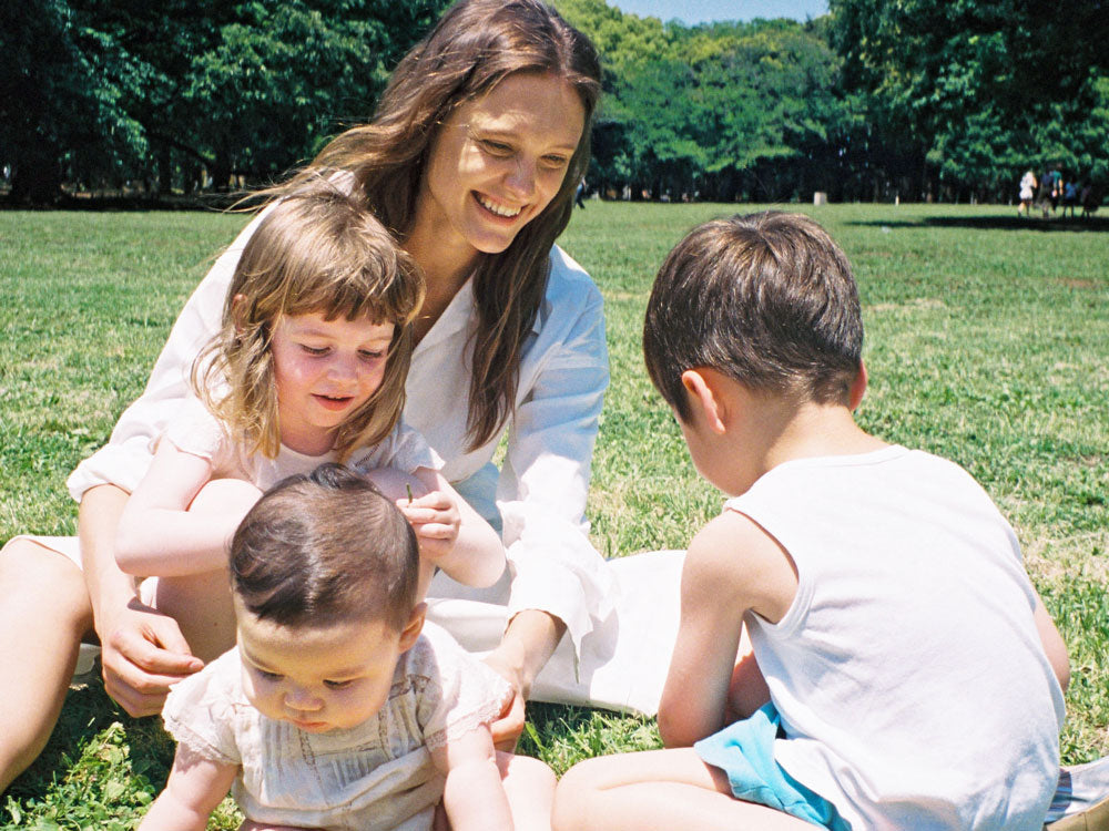 夏のレジャーで親子が笑顔でUVカットクリームを塗りながら楽しそうに座っている様子