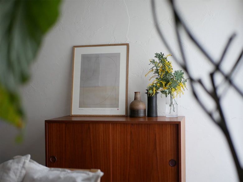 オーク材とブラックアルミニウム製のMOEBE FRAMEフレームが花鉢や木製家具とともに配置されたスタイリッシュな室内インテリア