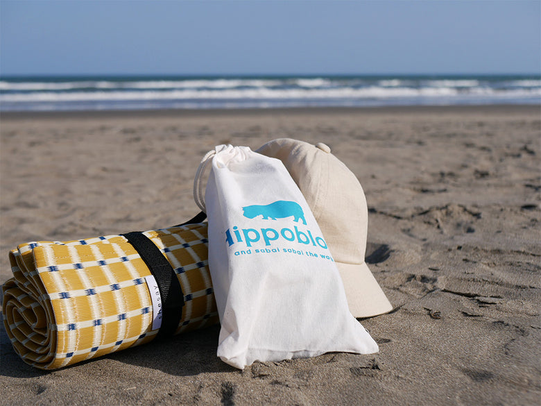 ヒッポブルーのビーチサンダルを履いた人々が砂浜を歩く海辺の風景