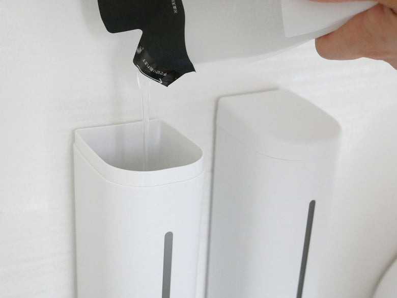 白色のマグネットソープディスペンサーとハンドドライヤーが設置された浴室の壁