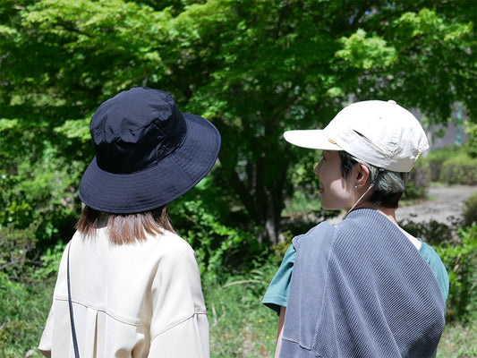 撥水加工が施された黒色フェドラスタイルの日傘ハット。調節可能なサイズとデオドラントタグが特徴で、夏のアウトドアに最適です。