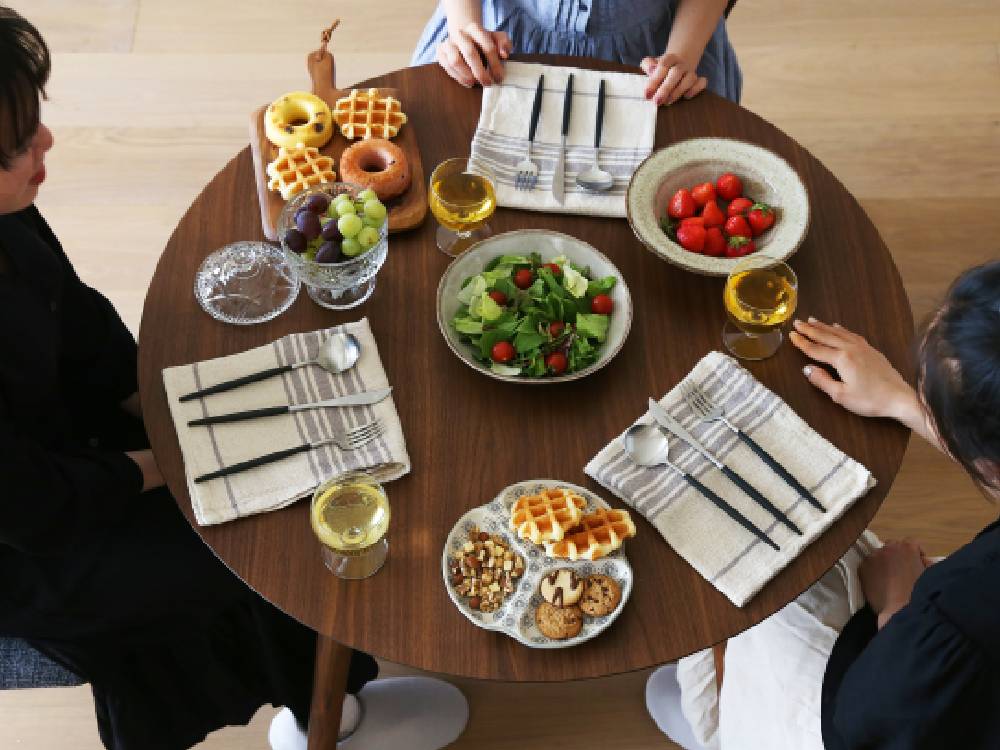 高野木工のMALLOONダイニングテーブルに、食器やサラダなどのテーブルウェアがセッティングされた様子