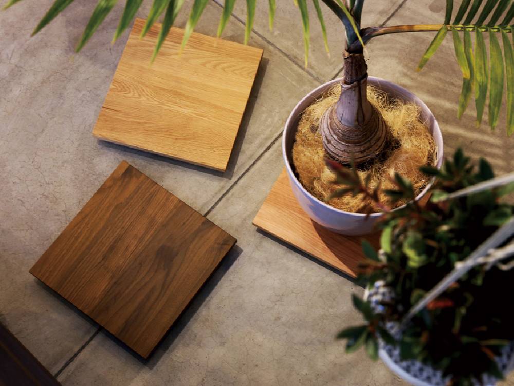 高野木工のホワイトオーク製プランターベースが木製フローリングの上に置かれ、花鉢が載っている様子