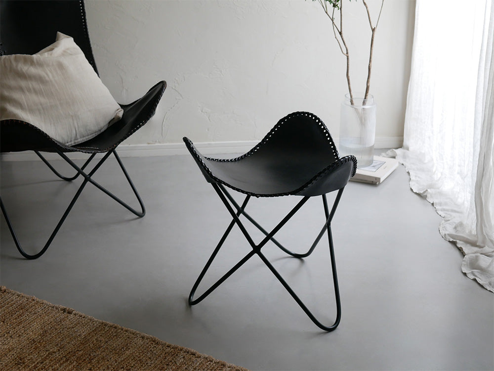 木製フロアのリビングルームに配置された、灰色のラップス製アイアンレザークラブチェア。快適なアームレスト付きでナチュラルな雰囲気を演出