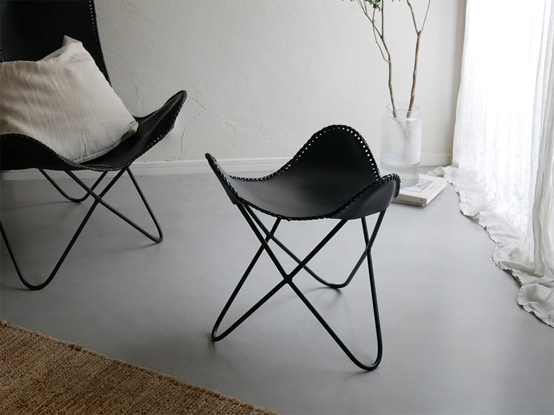 木製フロアのリビングルームに配置された、灰色のラップス製アイアンレザークラブチェア。快適なアームレスト付きでナチュラルな雰囲気を演出