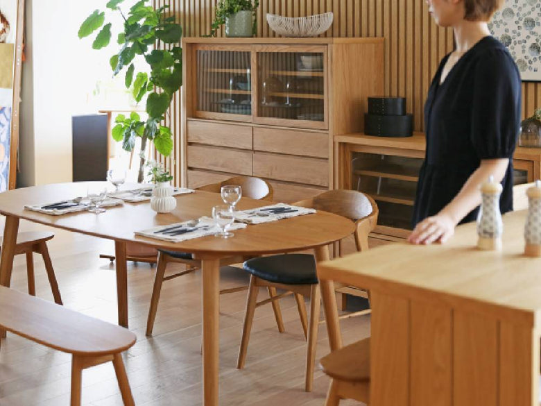 ホワイトオークまたはウォルナット製の高野木工RUBEダイニングテーブルが木製フロアと棚と共にダイニングルームに配置されている様子