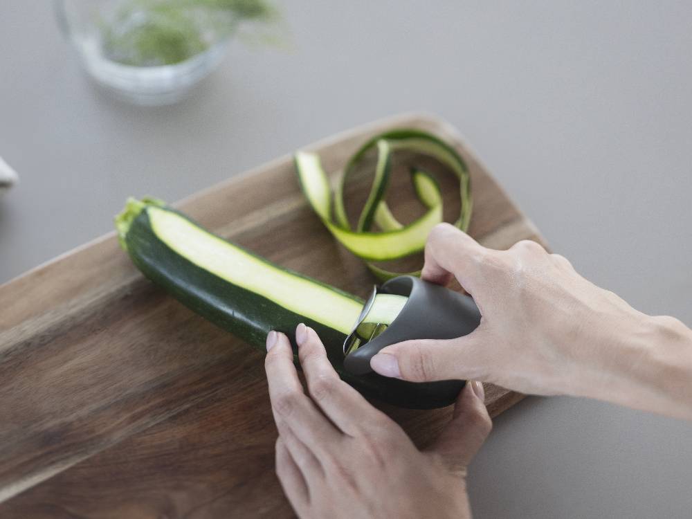 ABS樹脂とステンレス製のマーナのきほんピーラーが、まな板の上に置かれた野菜とともにキッチンで使用されている様子