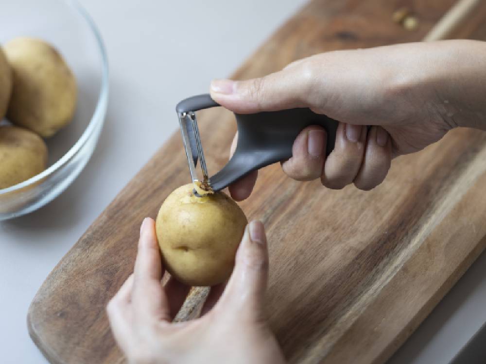 マーナのきほん ピーラーと新鮮な野菜や果物がカッティングボード上に並べられたキッチン用品の画像