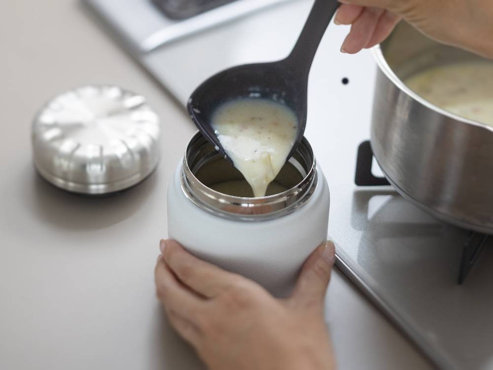 ナイロンとシリコーンゴム製の【marna/マーナ】マーナのきほん お玉がテーブルウェアや牛乳、アーモンドミルクと共にキッチンに配置されている様子